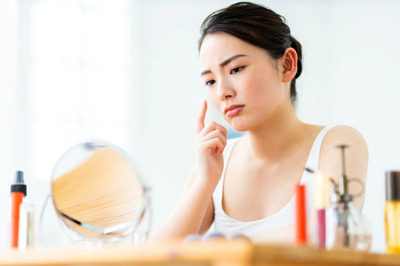 繰り返すニキビに悩み頬を気にする女性